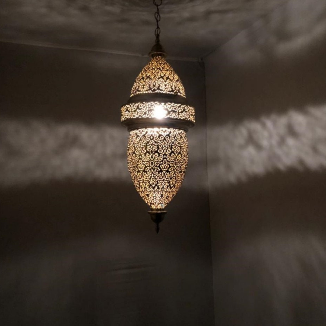 Hilal brass ceiling light with crescent inspired pendant shape casting soft golden patterns across a bedroom ceiling.