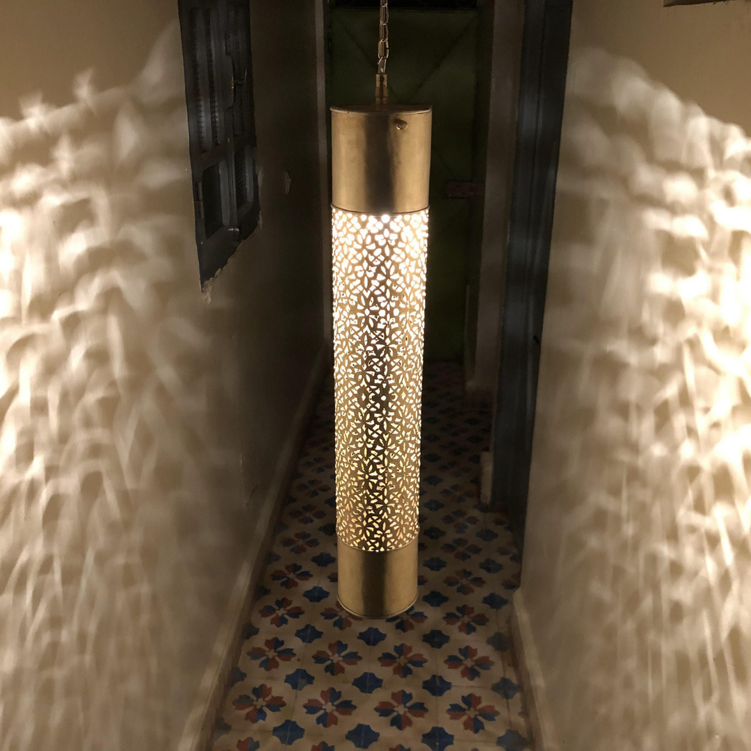 Qadouss brass ceiling light with lantern pendant shape casting warm patterned glow across a bedroom ceiling.