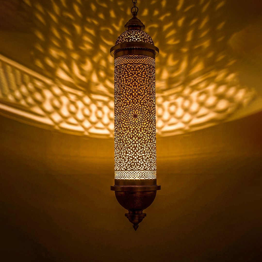 Rahma brass ceiling light with patterned metal detail spreading warm golden illumination over dining rooms and calm bedroom spaces.