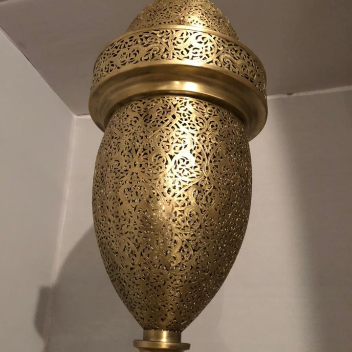 Hilal Moroccan brass lamp displayed in a riad interior with crescent profile and warm decorative ambience.