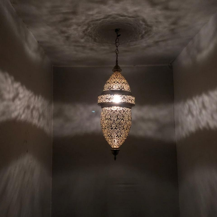 Angled Hilal ceiling fixture highlighting moon shaped brass form, polished surface, and artisan pattern detail.