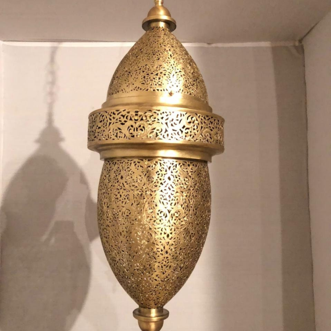 Bottom view of Hilal ceiling light showing curved brass shade detail and soft glow falling into the room.