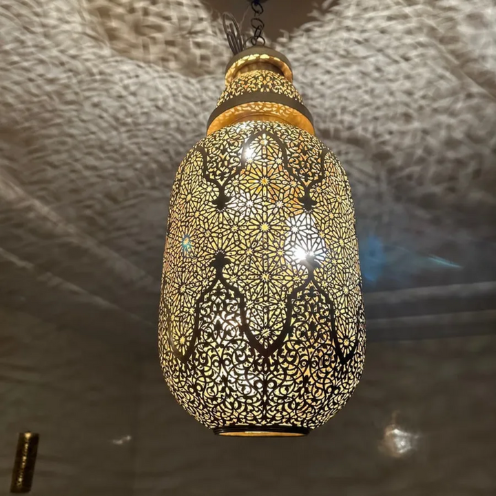 Jamila brass pendant lamp with Moroccan metal texture and golden tone for cozy bedroom lighting and refined ceiling decor.