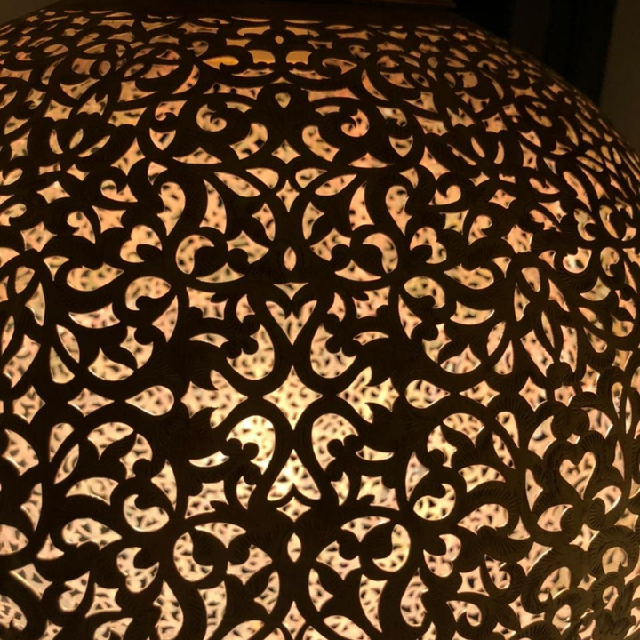 Angled Koora ceiling fixture highlighting spherical brass body, polished surface, and delicate pierced pattern.