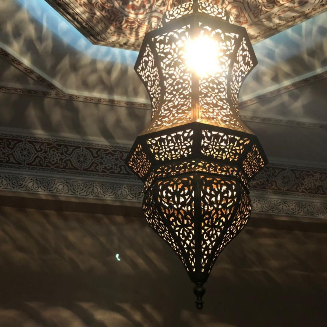 Najwa handmade brass lamp above a dining table with golden finish, soft light, and elegant overhead style.