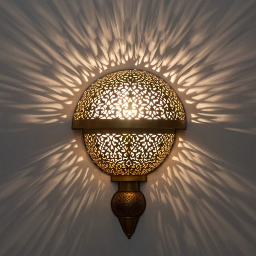 Noura golden brass wall lamp with curved form for warm bedroom ambience.