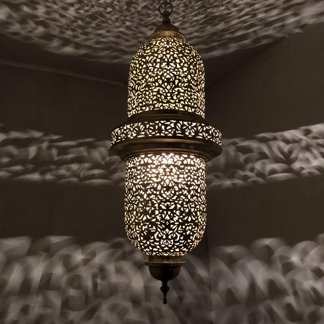 Salim brass ceiling light with crafted pendant shade casting warm patterned reflections across a bedroom ceiling.
