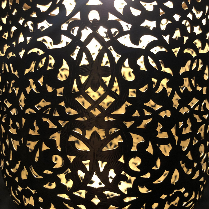 Salim Moroccan hanging lamp suspended from ceiling with ornate brass detail and mellow glow underneath.