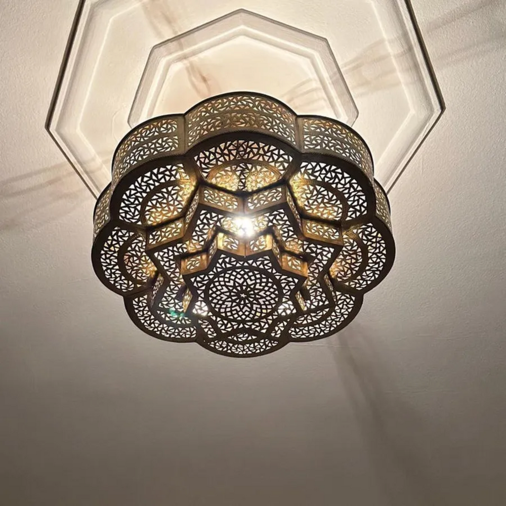 Flower shaped brass pendant lamp casting warm shadow reflections for boutique restaurant interior design.